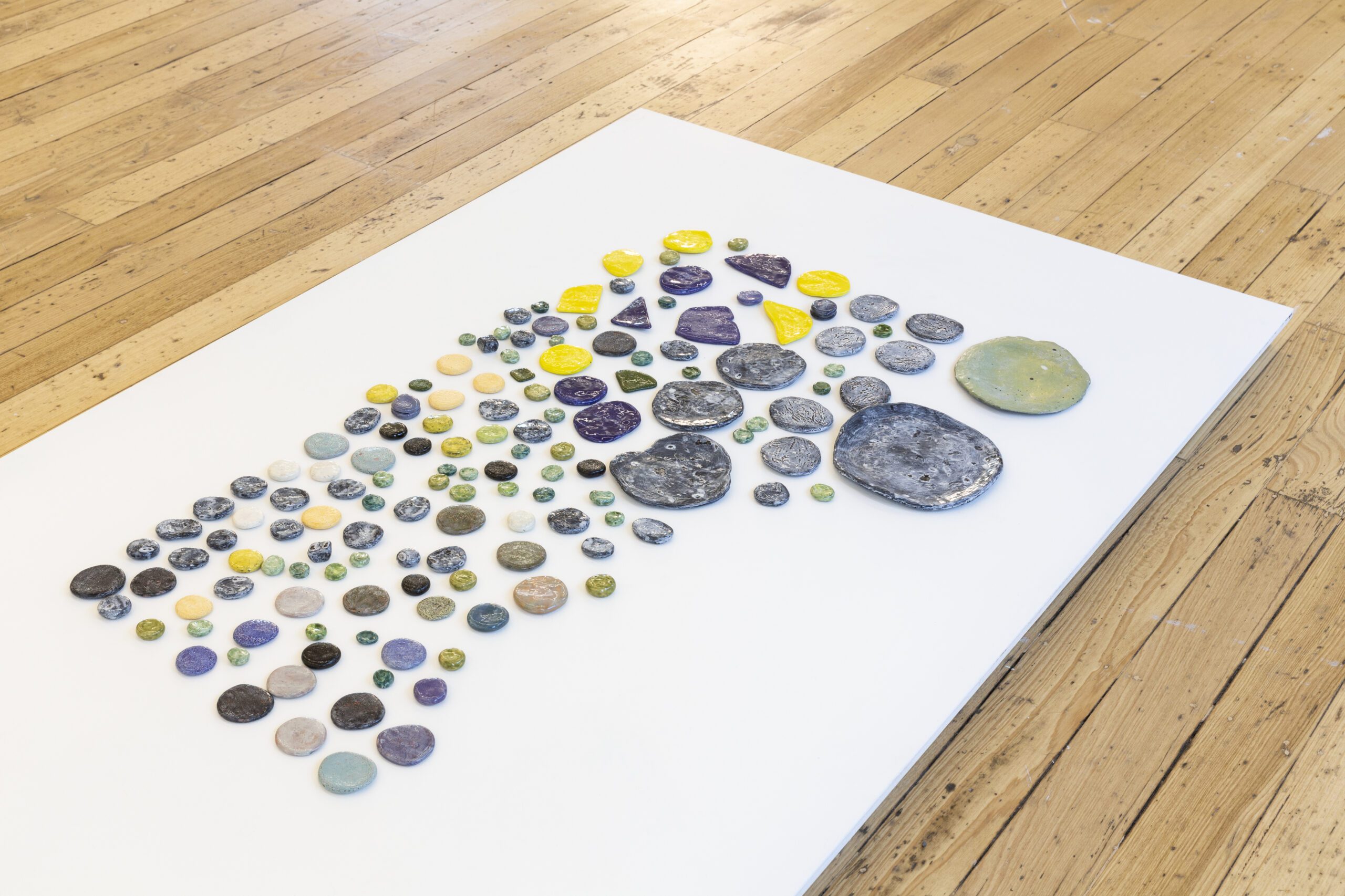 Numerous small circle ceramics displayed on a flat white surface