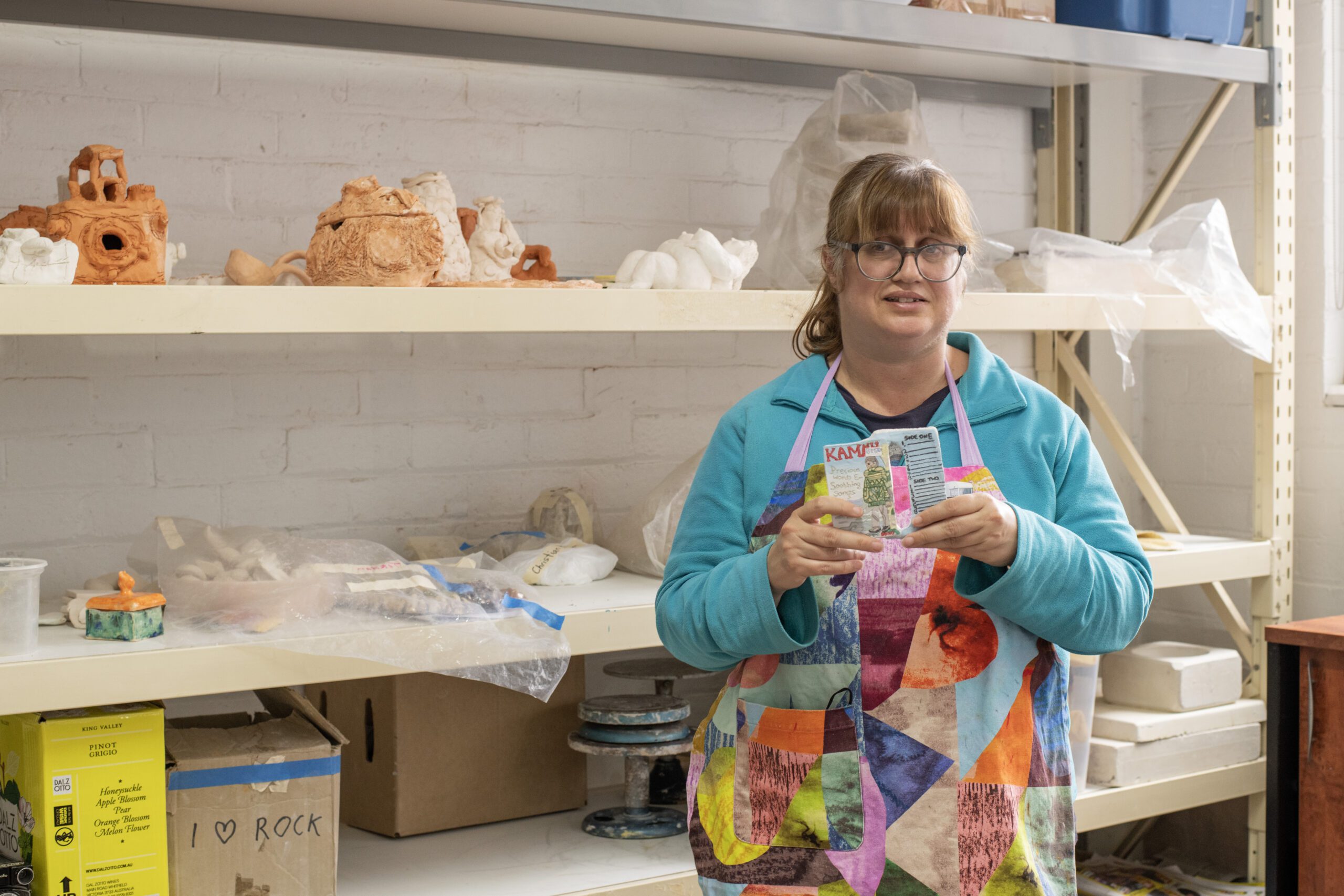 Lisa Reid holding her ceramic work in the Arts Project Australia studio